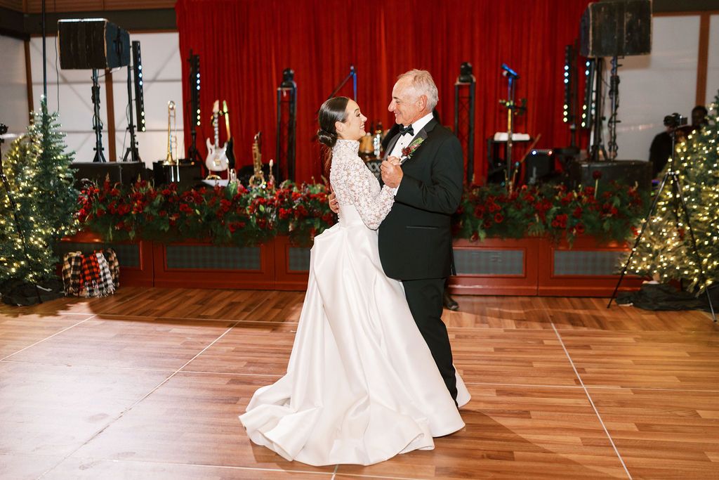 Moncus Park Christmas wedding: bride dancing on the pavilion dance floor in front of a stage with red curtains
