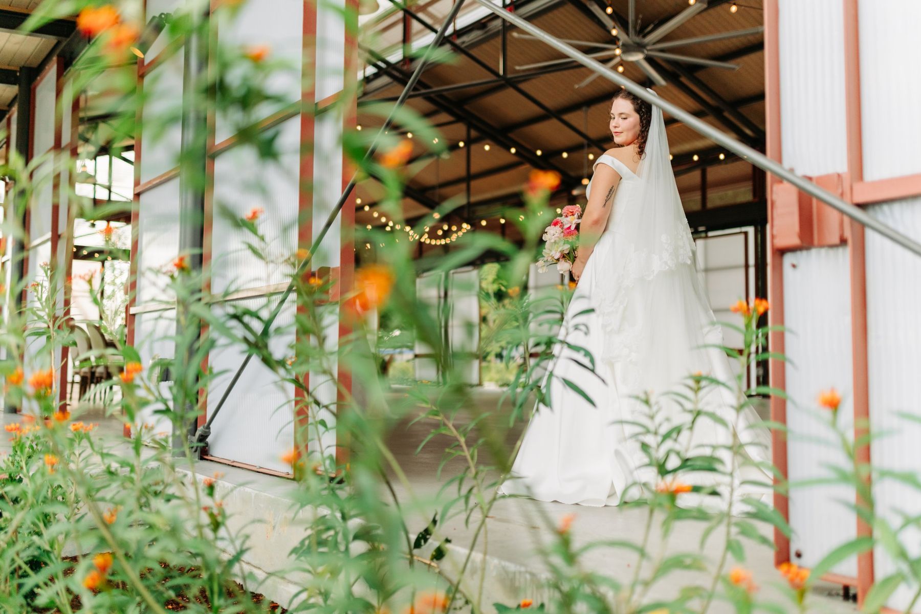 Moncus Park: bride holding a pink bouquet inside the Doerle Pavilion under string lights