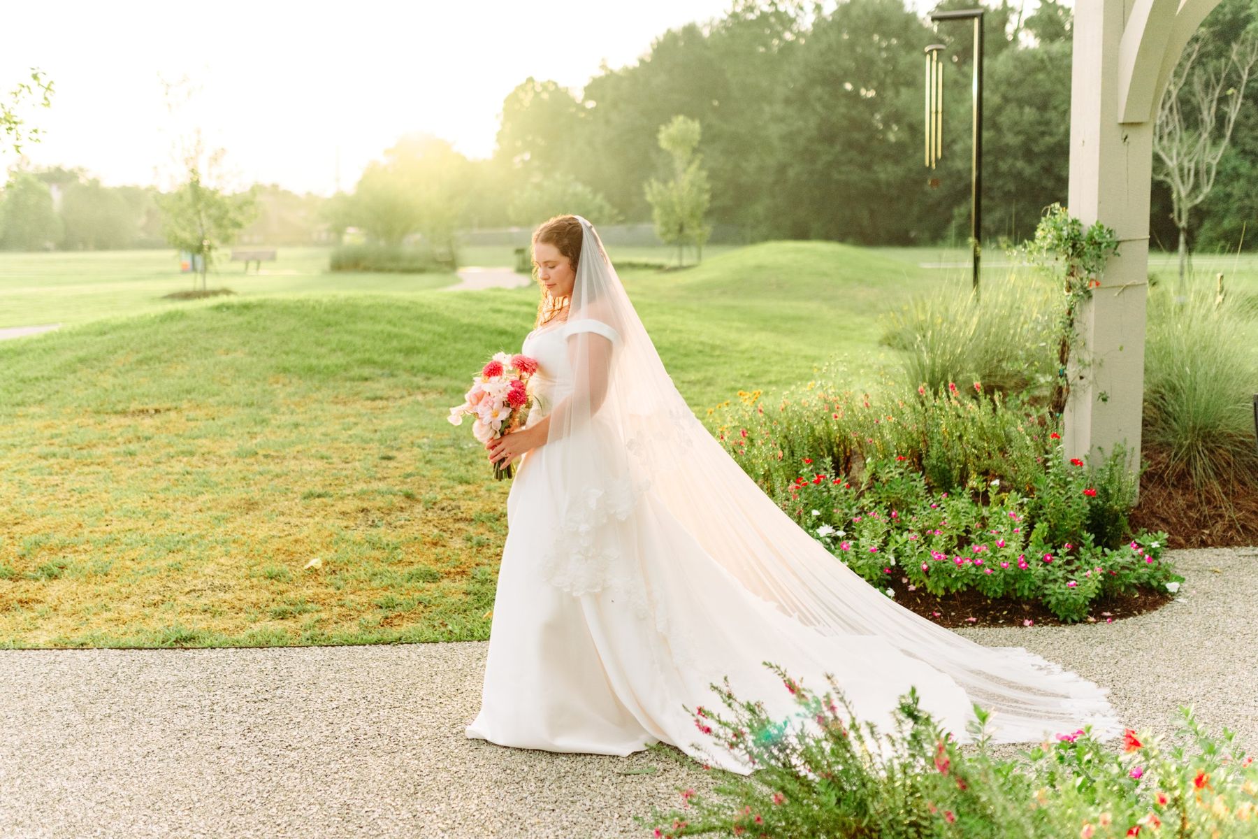 Moncus Park: bride in a long veil walking through the garden at golden hour
