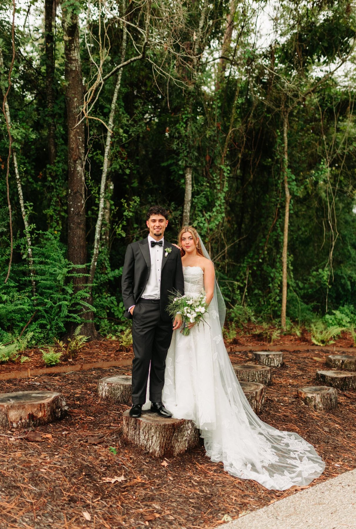 Moncus Park: couple standing on a tree stump in a wooded garden with stump seating